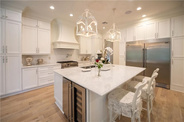 kitchen with premium appliances, custom exhaust hood, sink, and white cabinets