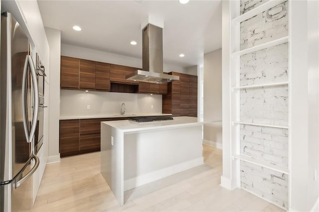 kitchen with island range hood, sink, stainless steel fridge, a center island, and light hardwood / wood-style flooring