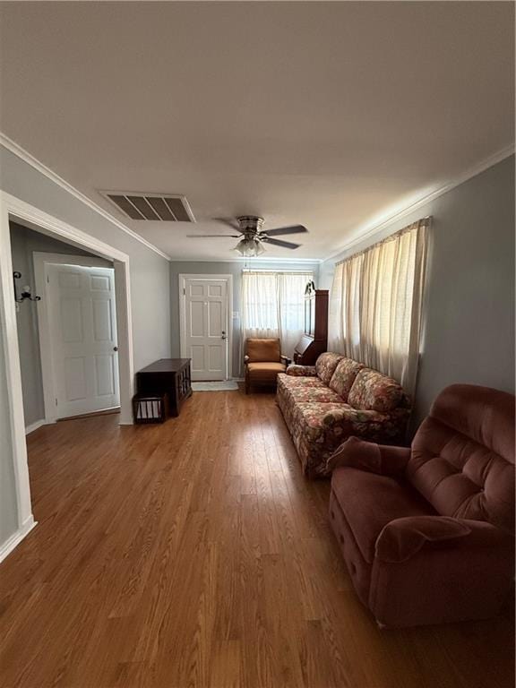 living room featuring hardwood / wood-style floors, crown molding, and ceiling fan