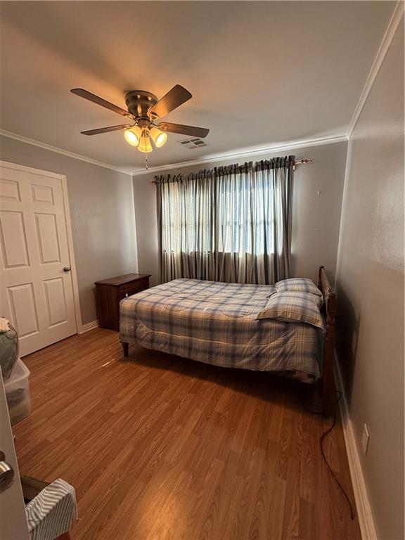 bedroom featuring hardwood / wood-style floors, ornamental molding, and ceiling fan