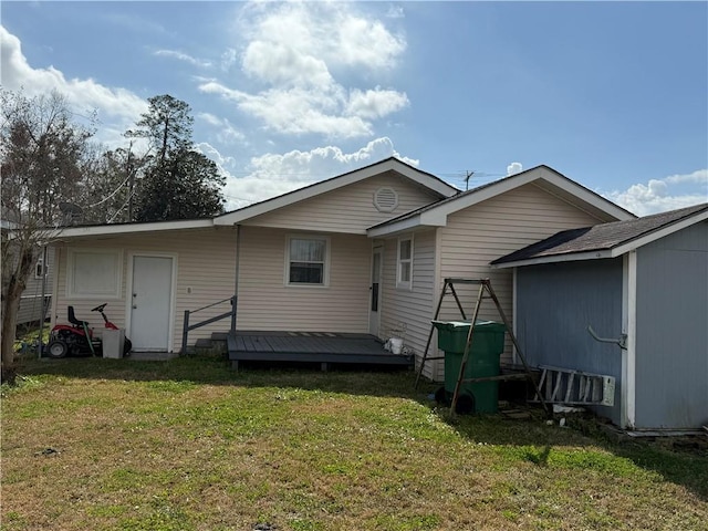 rear view of house featuring a wooden deck and a lawn