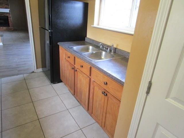 kitchen featuring black fridge, sink, and light tile patterned floors