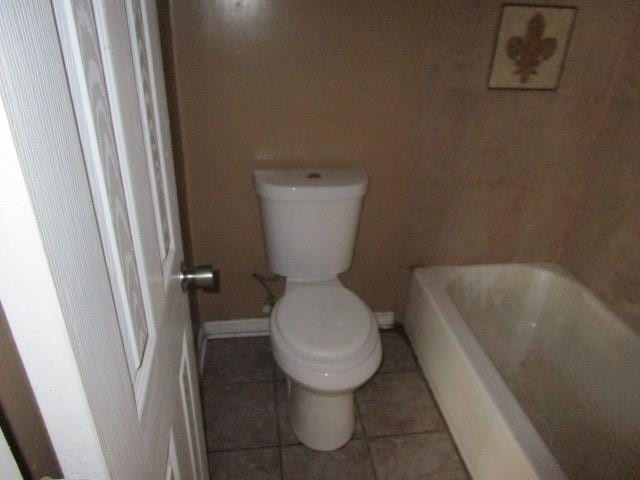 bathroom featuring tile patterned flooring, a washtub, and toilet