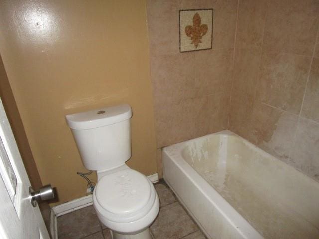 bathroom featuring tile patterned flooring, a tub, and toilet