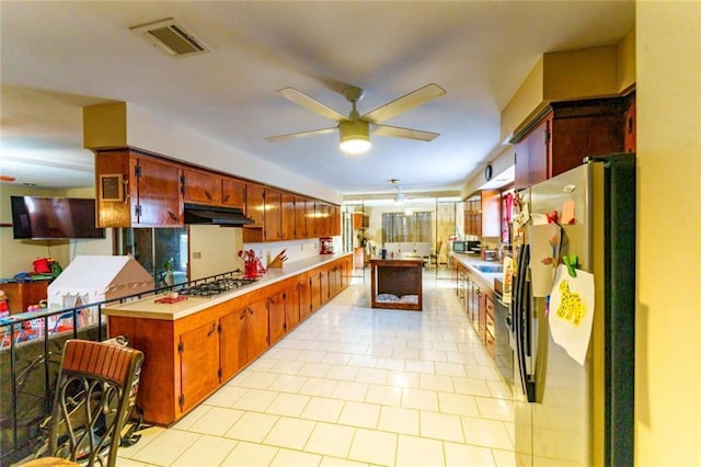 kitchen with appliances with stainless steel finishes, light tile patterned floors, ceiling fan, and kitchen peninsula