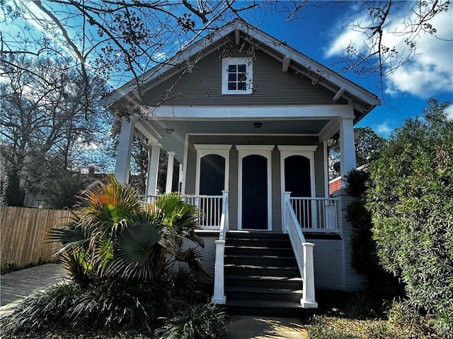 view of front of house featuring covered porch and fence