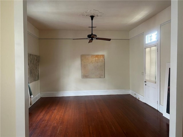 empty room featuring ceiling fan, visible vents, baseboards, and wood finished floors