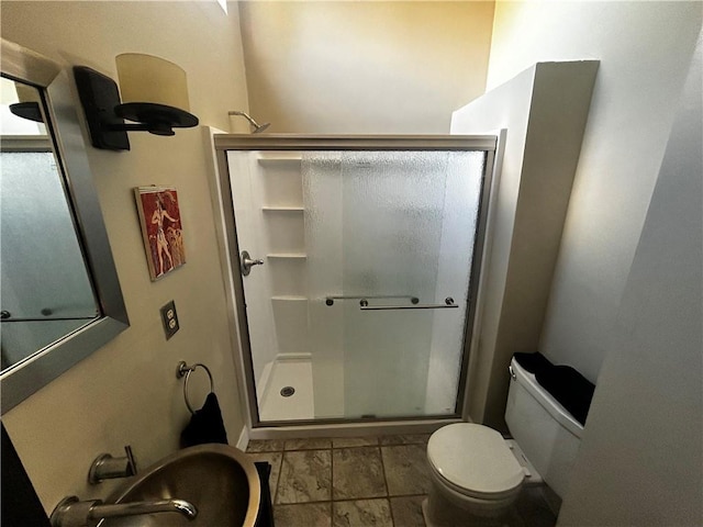 full bath featuring a stall shower, a sink, and toilet