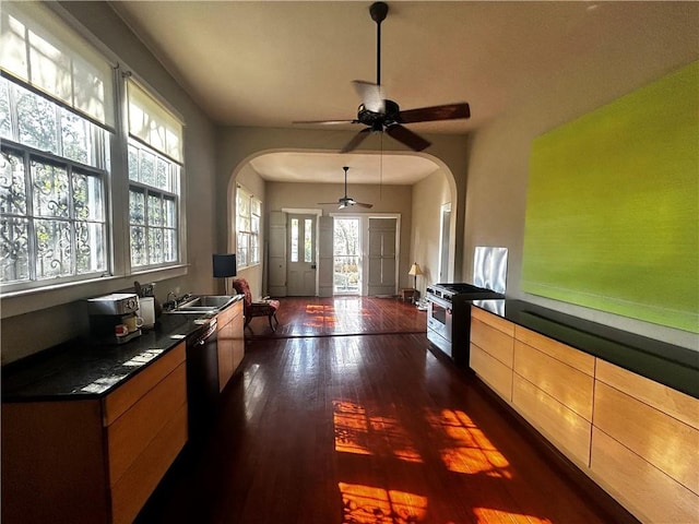 foyer entrance featuring dark wood-type flooring, arched walkways, and a ceiling fan