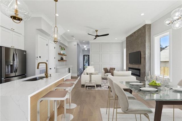 kitchen featuring pendant lighting, white cabinetry, sink, and stainless steel fridge with ice dispenser