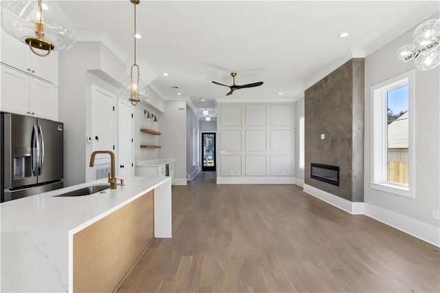 kitchen featuring stainless steel fridge with ice dispenser, decorative light fixtures, a large fireplace, and sink