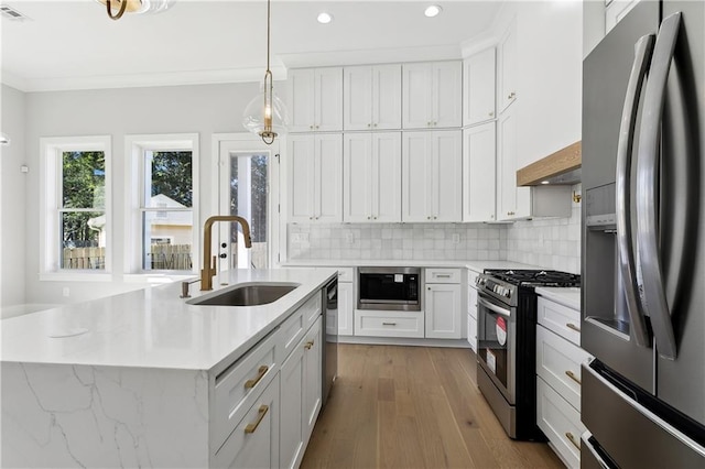 kitchen with decorative light fixtures, white cabinetry, sink, a kitchen island with sink, and stainless steel appliances