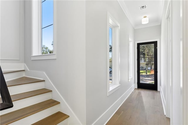 entrance foyer with light hardwood / wood-style flooring, crown molding, and plenty of natural light