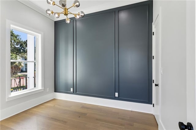 spare room featuring a notable chandelier and light hardwood / wood-style floors