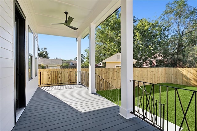 wooden terrace featuring ceiling fan and a lawn