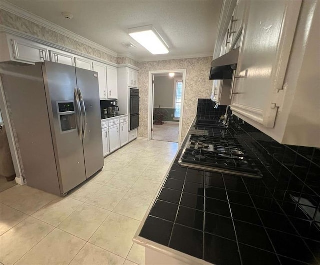 kitchen with white cabinetry, stainless steel fridge, exhaust hood, and tile countertops