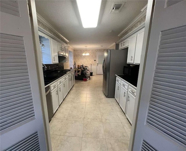 kitchen featuring white cabinetry, crown molding, light tile patterned floors, pendant lighting, and stainless steel appliances