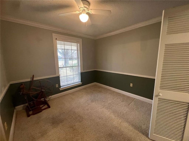 carpeted empty room featuring ceiling fan, ornamental molding, and a textured ceiling