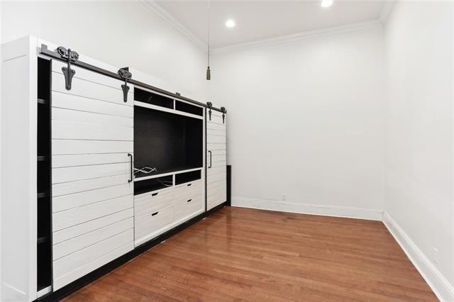 unfurnished bedroom featuring hardwood / wood-style floors, ornamental molding, and a barn door