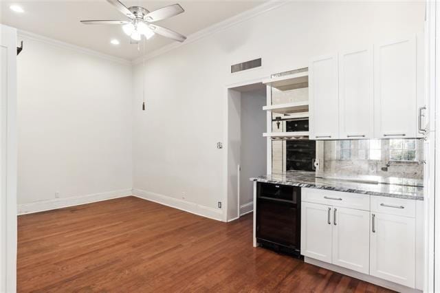 kitchen featuring dark hardwood / wood-style floors, white cabinets, decorative backsplash, ornamental molding, and light stone counters