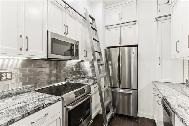 kitchen featuring white cabinetry, backsplash, stainless steel appliances, dark hardwood / wood-style floors, and light stone countertops