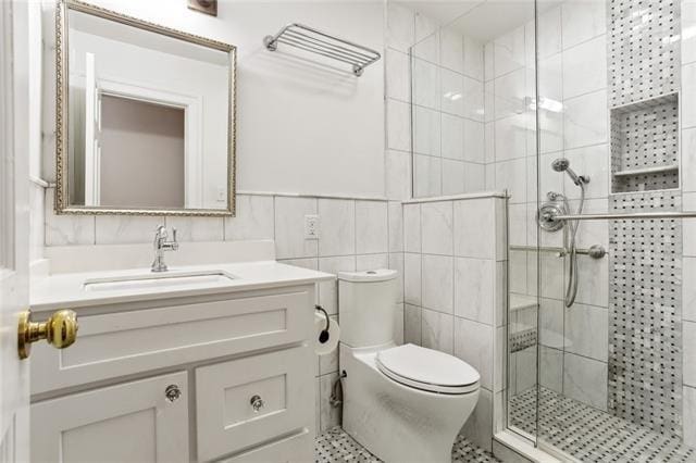 bathroom featuring vanity, tile walls, walk in shower, and toilet