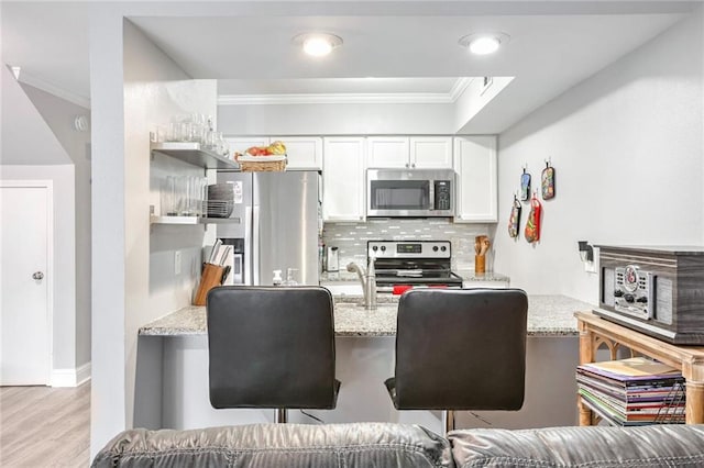 kitchen featuring appliances with stainless steel finishes, white cabinets, light stone counters, and decorative backsplash