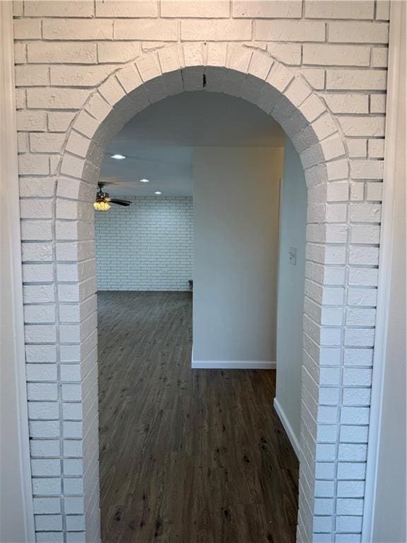 hallway featuring brick wall and dark wood-type flooring