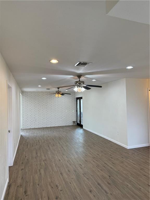 unfurnished living room with ceiling fan, brick wall, and dark hardwood / wood-style flooring