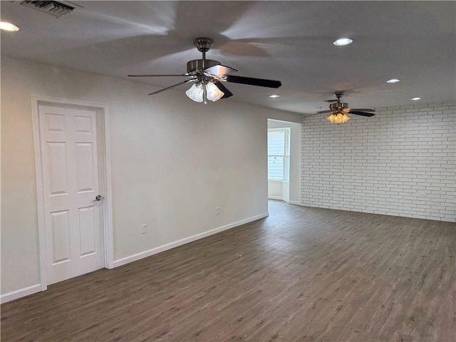 empty room with ceiling fan, brick wall, and dark hardwood / wood-style flooring