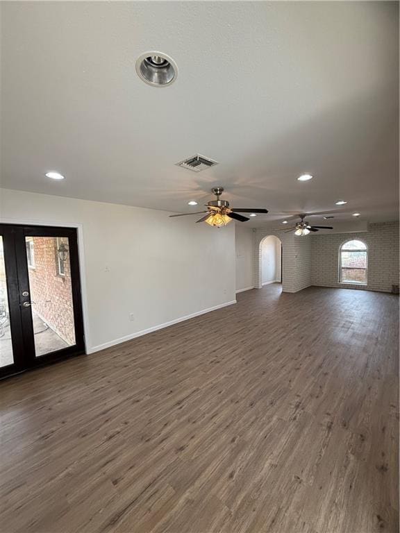 unfurnished living room featuring dark wood-type flooring and ceiling fan