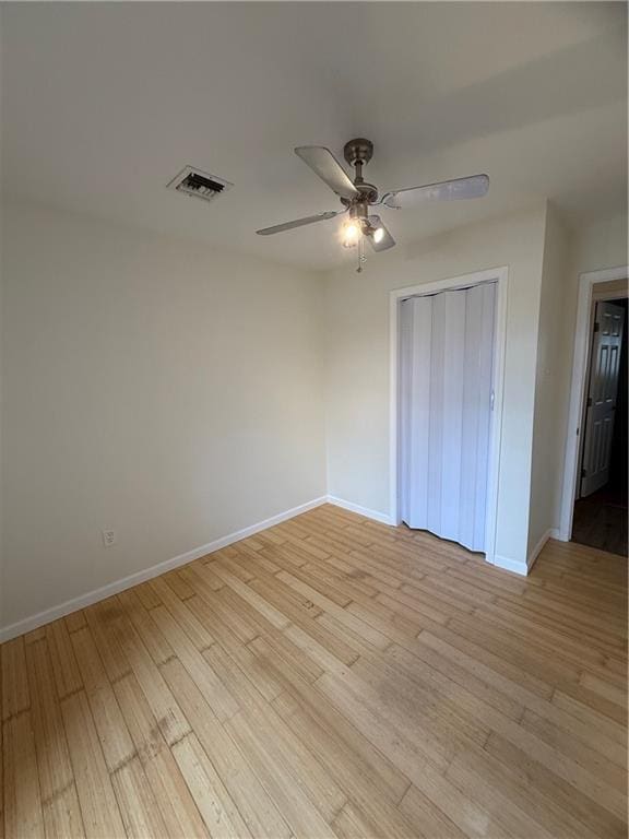 unfurnished bedroom with ceiling fan, light wood-type flooring, and a closet