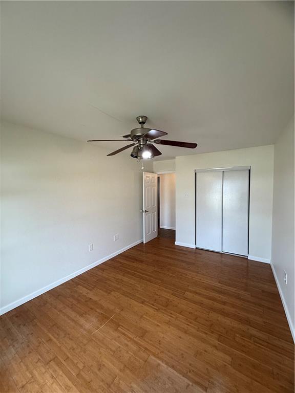 unfurnished bedroom featuring hardwood / wood-style floors, a closet, and ceiling fan