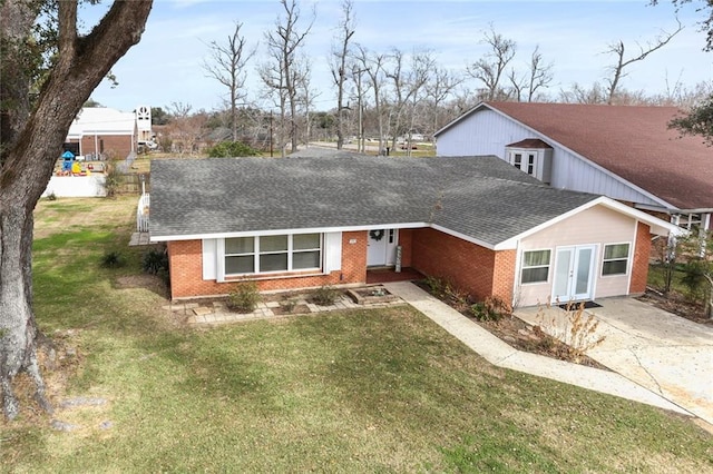 view of front facade featuring french doors, brick siding, a front lawn, and a shingled roof