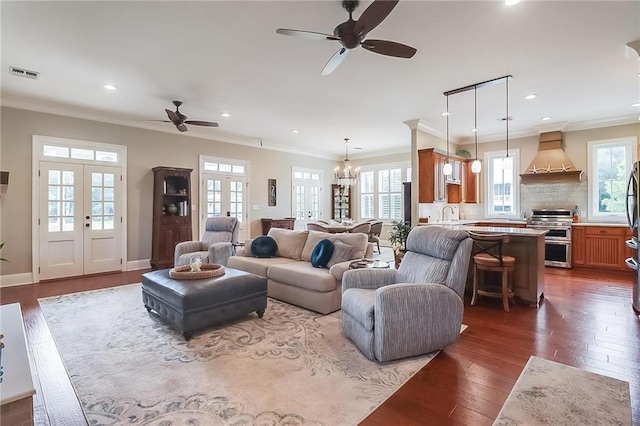 living room featuring ceiling fan with notable chandelier, sink, crown molding, dark wood-type flooring, and french doors