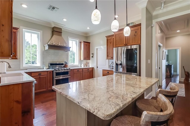 kitchen featuring a kitchen island, sink, stainless steel appliances, light stone countertops, and custom range hood