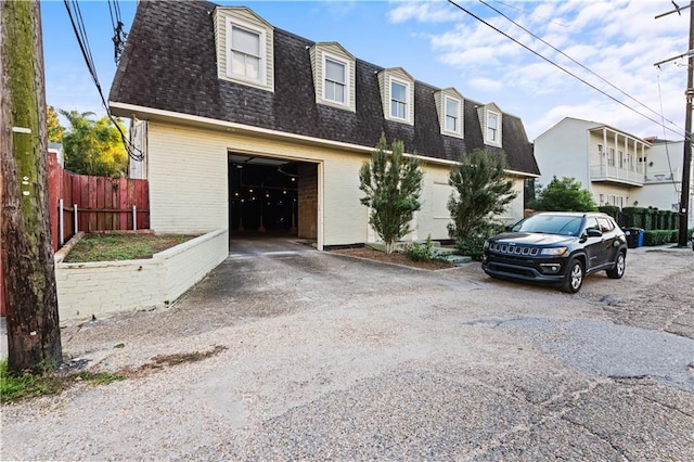 view of property with a garage, brick siding, fence, driveway, and roof with shingles