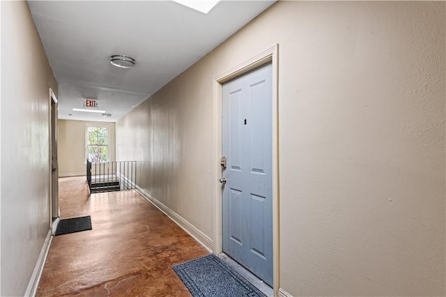 corridor with concrete flooring, an upstairs landing, and baseboards