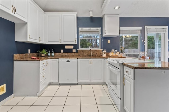 kitchen featuring light tile patterned floors, white appliances, dark stone counters, and white cabinets