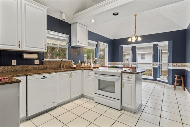 kitchen featuring sink, white appliances, white cabinetry, dark stone countertops, and kitchen peninsula