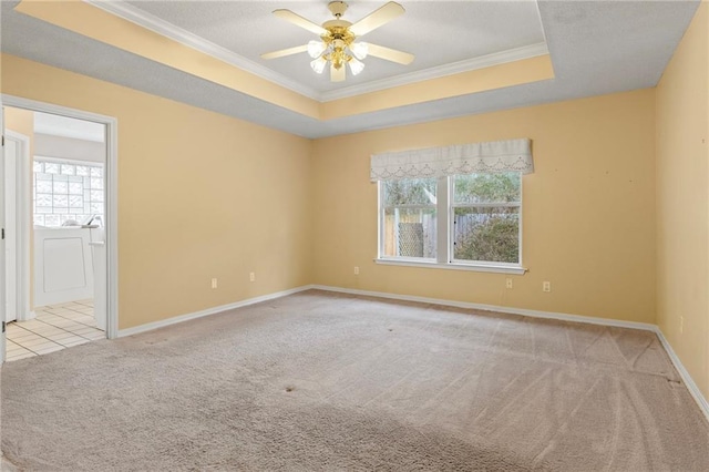 empty room featuring ceiling fan, ornamental molding, a tray ceiling, and light carpet