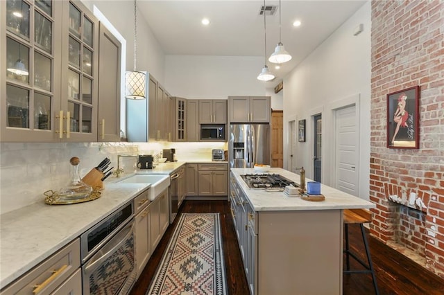 kitchen with a center island, hanging light fixtures, a kitchen breakfast bar, stainless steel appliances, and decorative backsplash