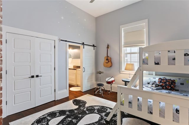 bedroom with dark hardwood / wood-style flooring, a closet, ensuite bath, and a barn door