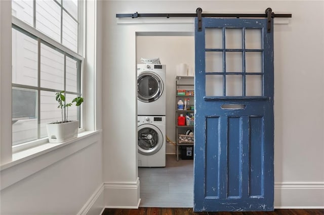 laundry area with dark hardwood / wood-style floors, stacked washer and dryer, and a barn door