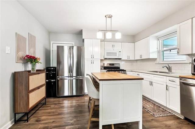 kitchen with decorative light fixtures, white cabinetry, sink, a center island, and stainless steel appliances