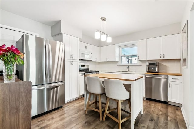 kitchen with sink, stainless steel appliances, a center island, and white cabinets