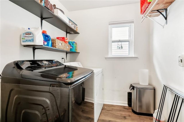 washroom with hardwood / wood-style flooring and washing machine and dryer