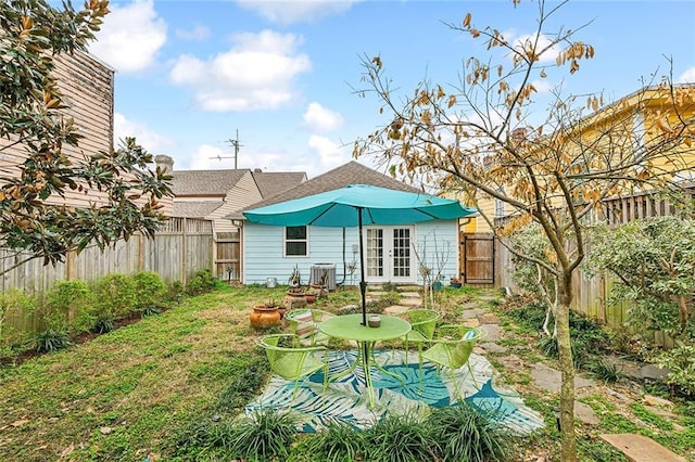 rear view of property with central AC unit, a yard, and french doors