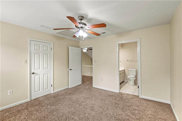 unfurnished bedroom featuring ceiling fan, light colored carpet, and ensuite bath