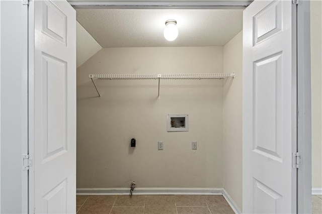 laundry area featuring electric dryer hookup, washer hookup, a textured ceiling, and light tile patterned floors